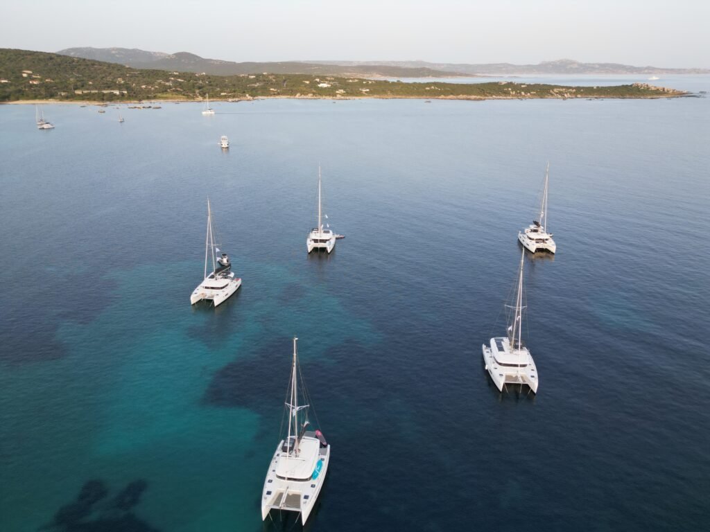 Vue aérienne de catamarans Isula-sail ancrés dans une baie de sable aux eaux turquoise de Corse du Sud